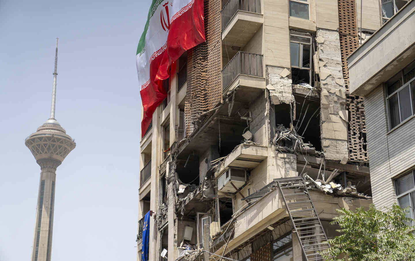 An Iranian flag is draped from a building damaged during a recent attack by Israel near Milad Tower in Tehran, Iran, on June 25, 2025.