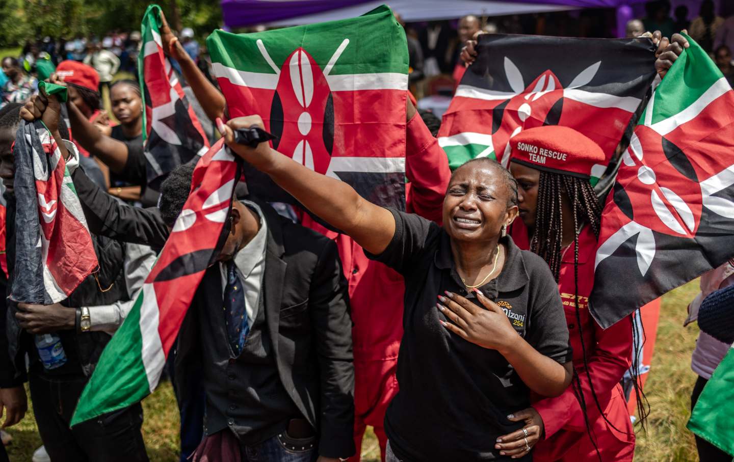 An activists reacts with emotion as she joins others holding Kenyan flags during the funeral of Boniface Kariuki, a street hawker who died from gunshot wounds days after being shot by Kenyan police during nationwide protests against police violence and government policies, in a village near Kangema on July 11, 2025.