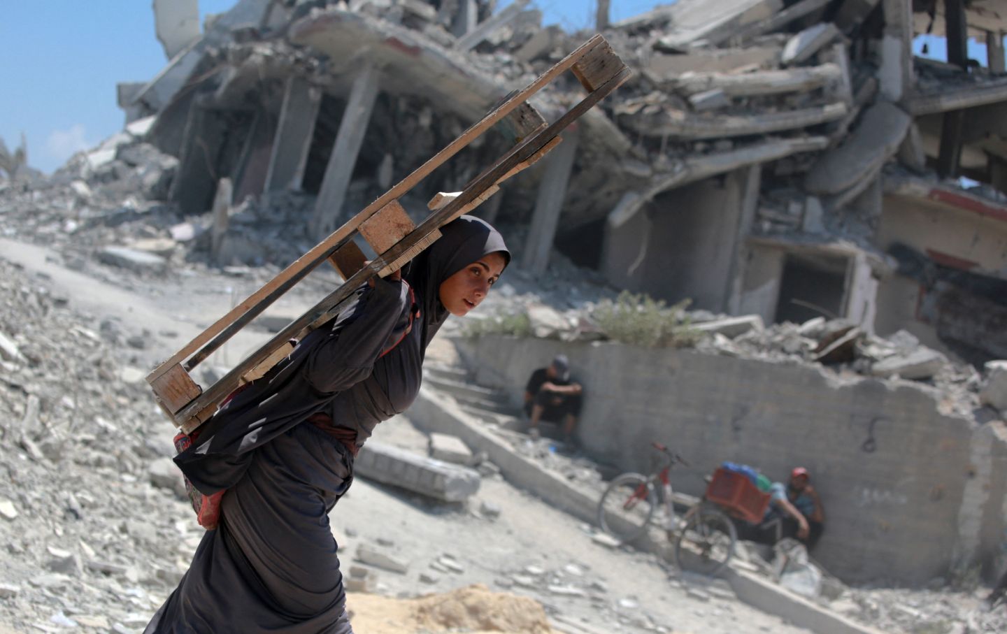 A Palestinian woman carries a wooden pallet as she returns from an area in which aid trucks entered Gaza through the Zikim crossing point, in Jabalia in the northern Gaza Strip on August 1, 2025.