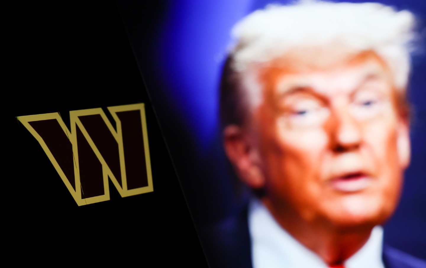 The Washington Commanders logo displayed on a phone screen next to a photo of Donald Trump